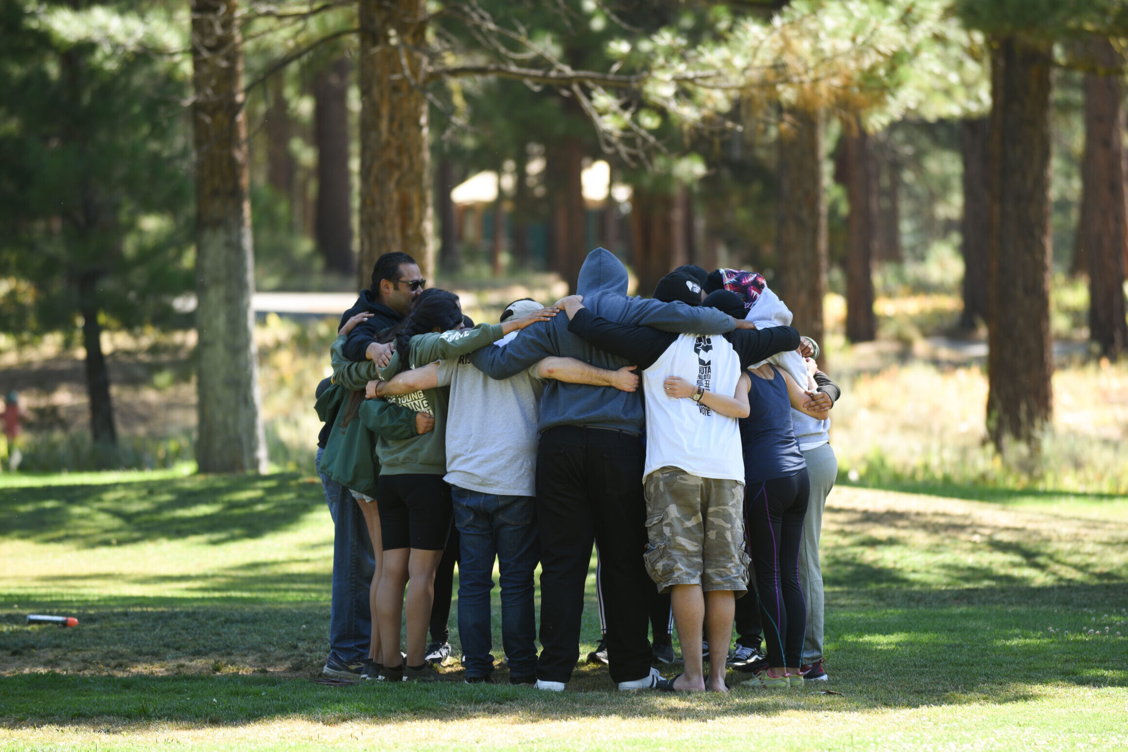 A group of kids in The President's Youth Council formed in a huddle with their arms wrapped around each other.