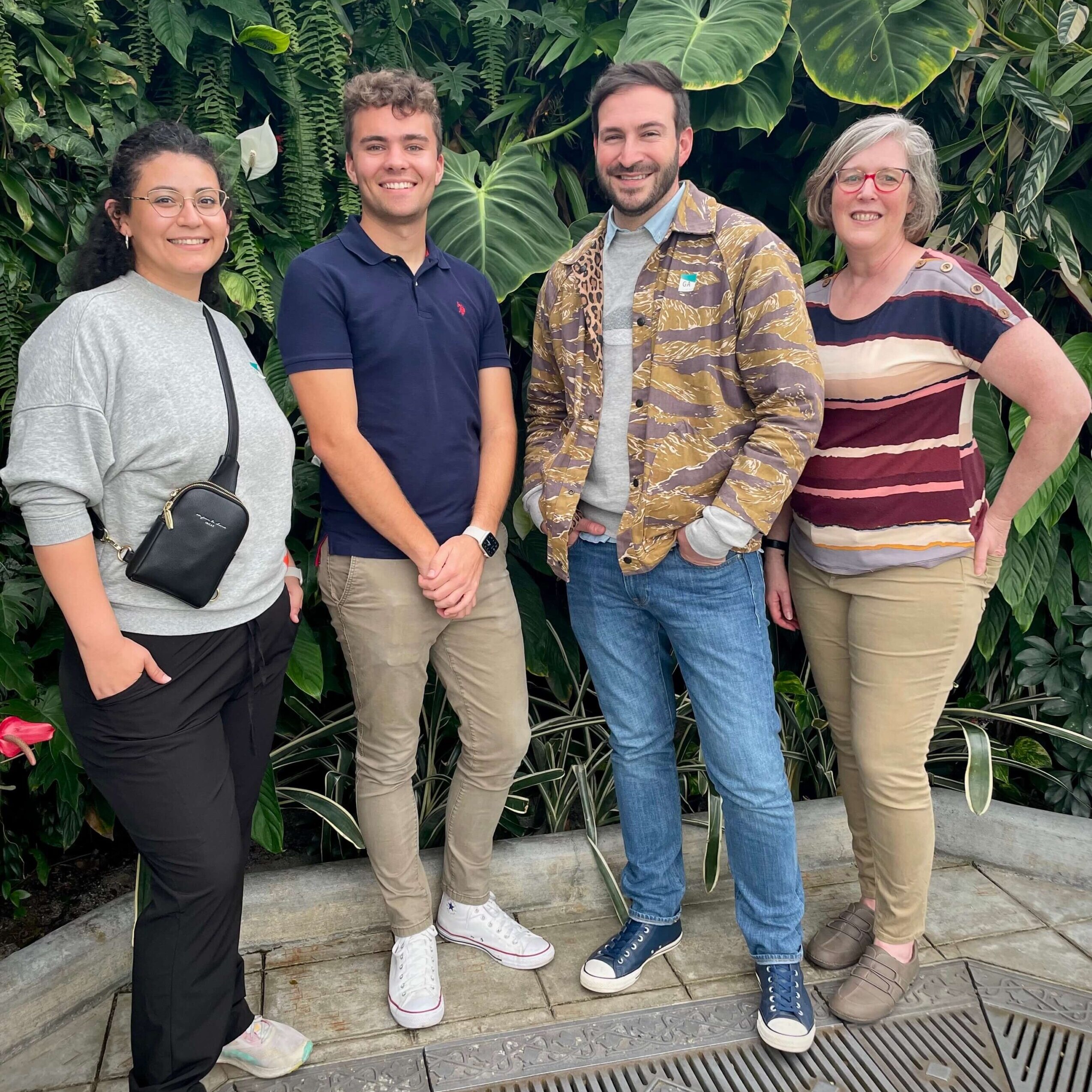 Four people stand in front of a wall of botanical greenery at the Conservatory of Flowers in San Francisco