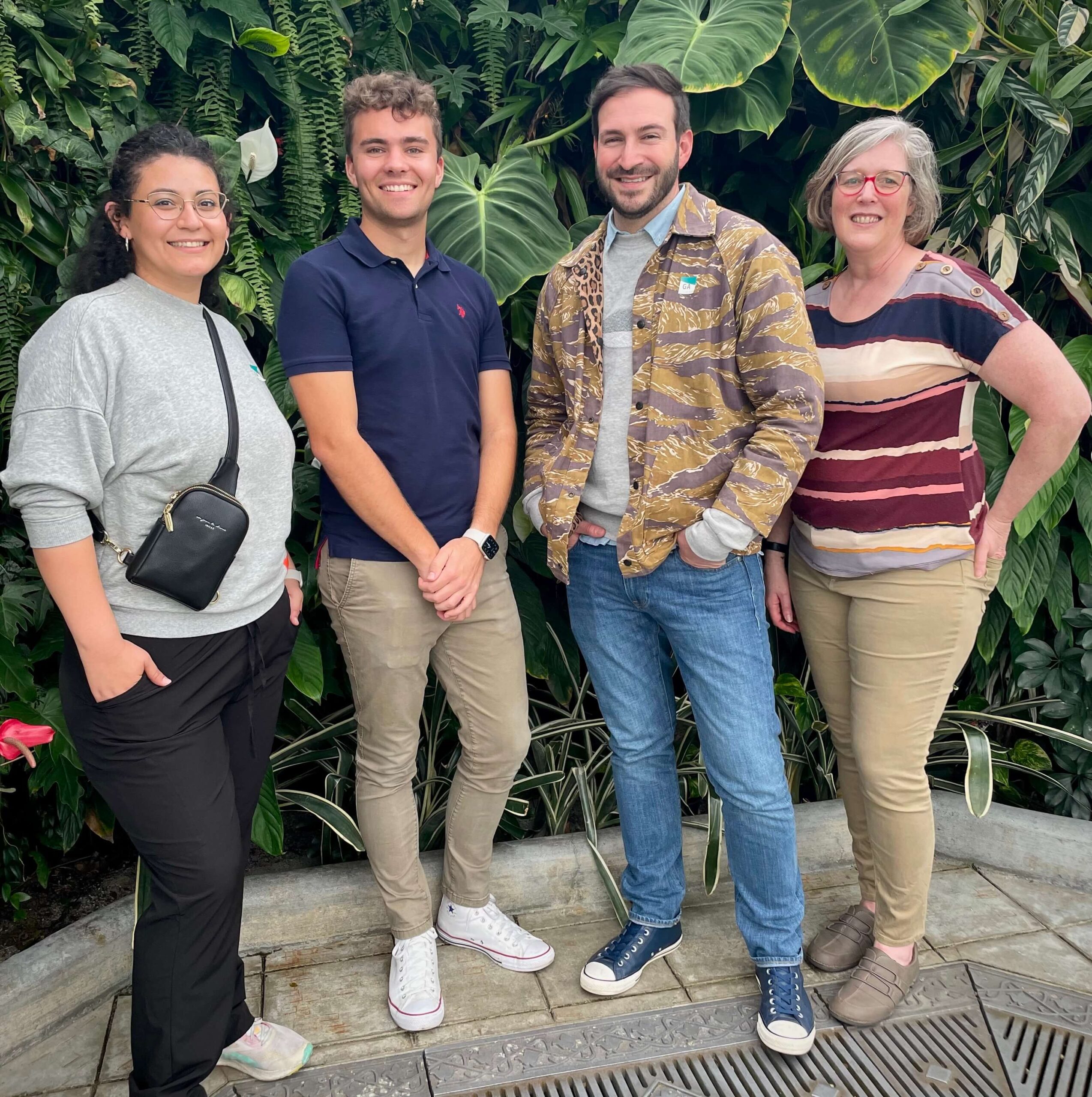 Four people stand in front of a wall of botanical greenery at the Conservatory of Flowers in San Francisco