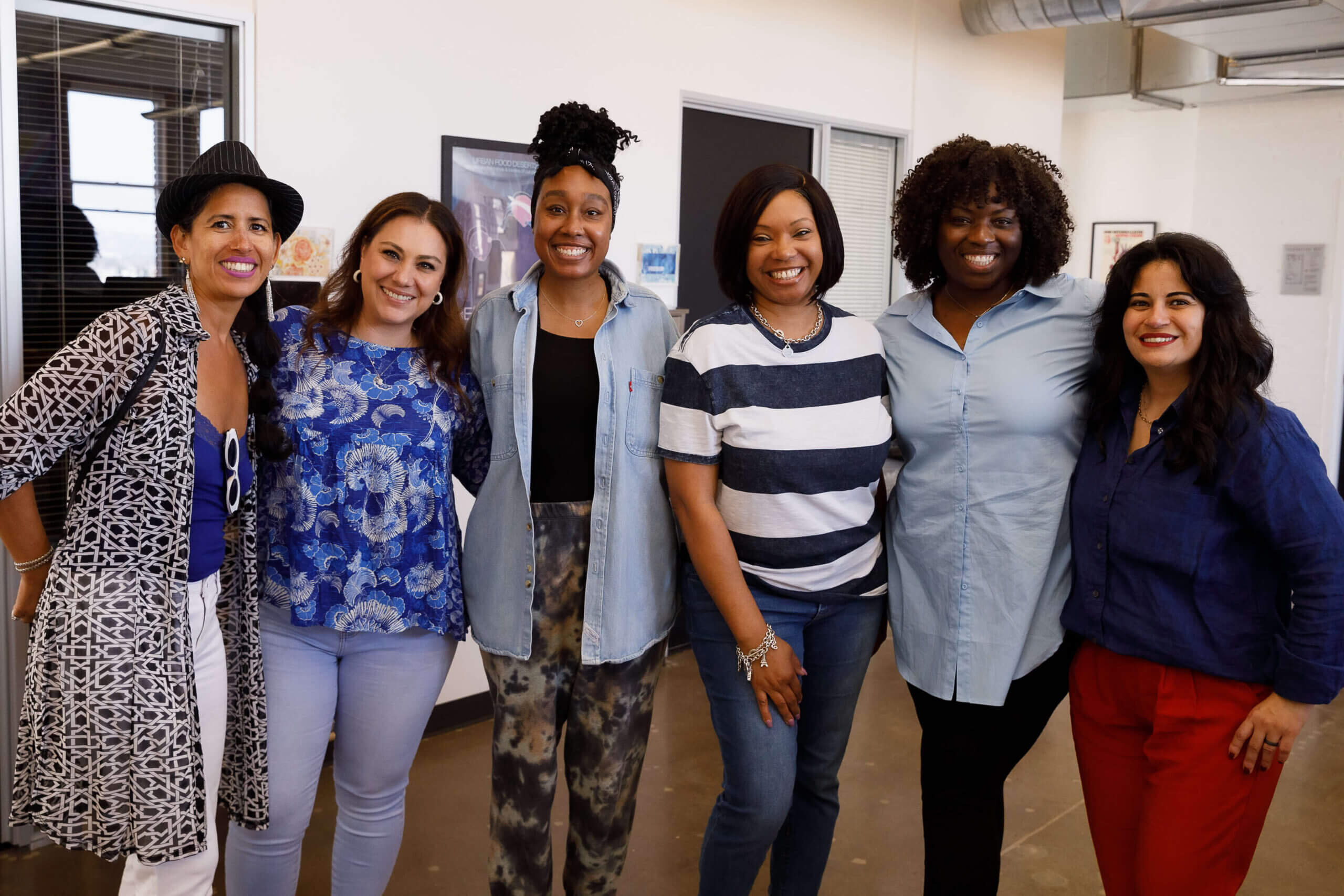 Six people wearing blue shirts pose for a photo in MSC's open concept office.